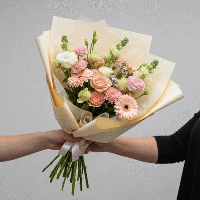 Close-up of a fresh, vibrant flower bouquet being delivered by a hand